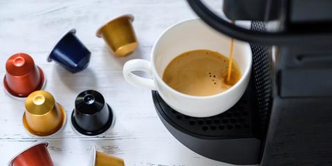café coulant d'une machine nespresos dans une tasse avec capsules colorées